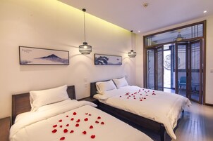 Habitación de hotel con dos camas, un ventanal con vistas y obras de arte en las paredes.
