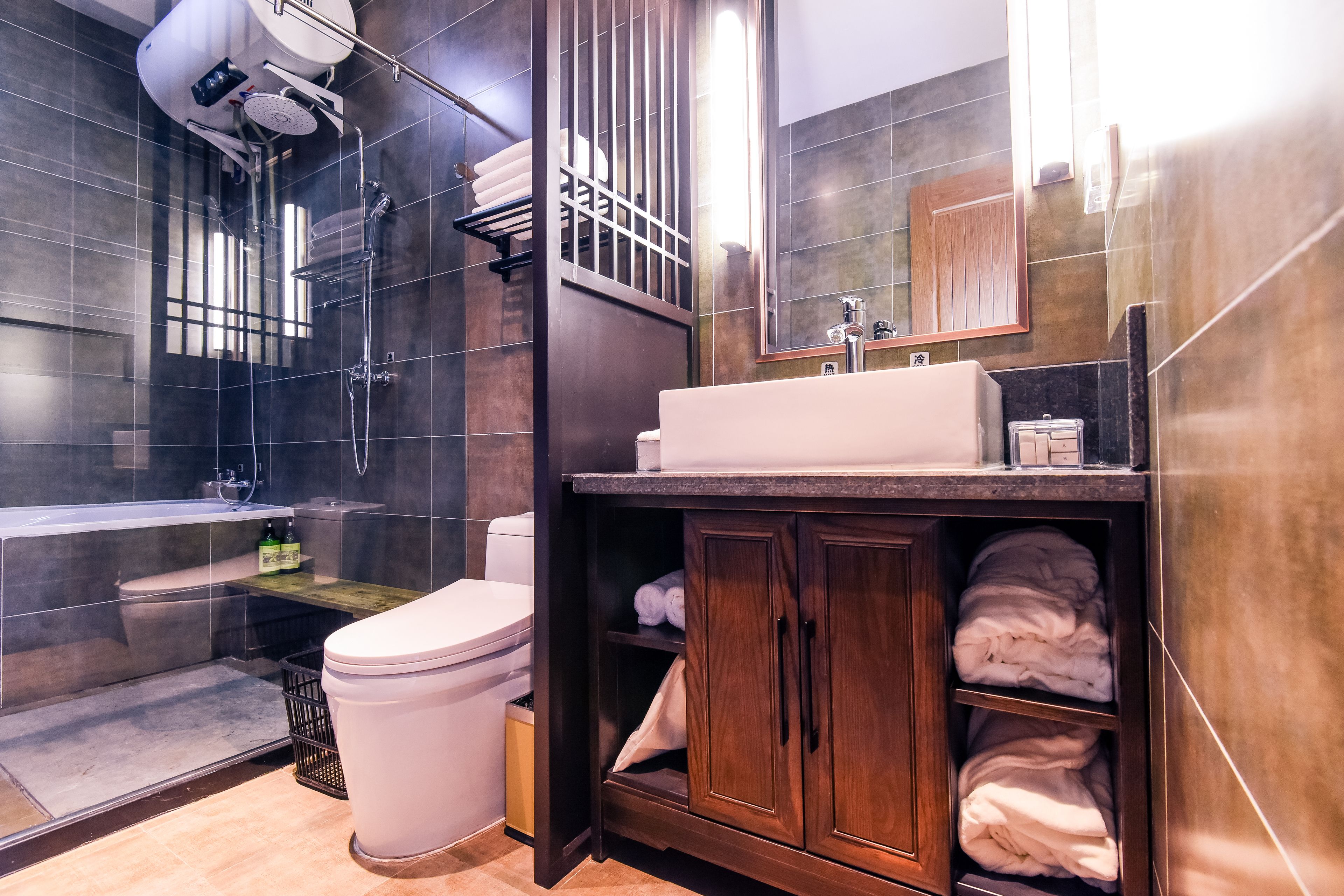 A modern bathroom with a glass-enclosed shower, a white toilet, and a wooden vanity with a sink and mirror.