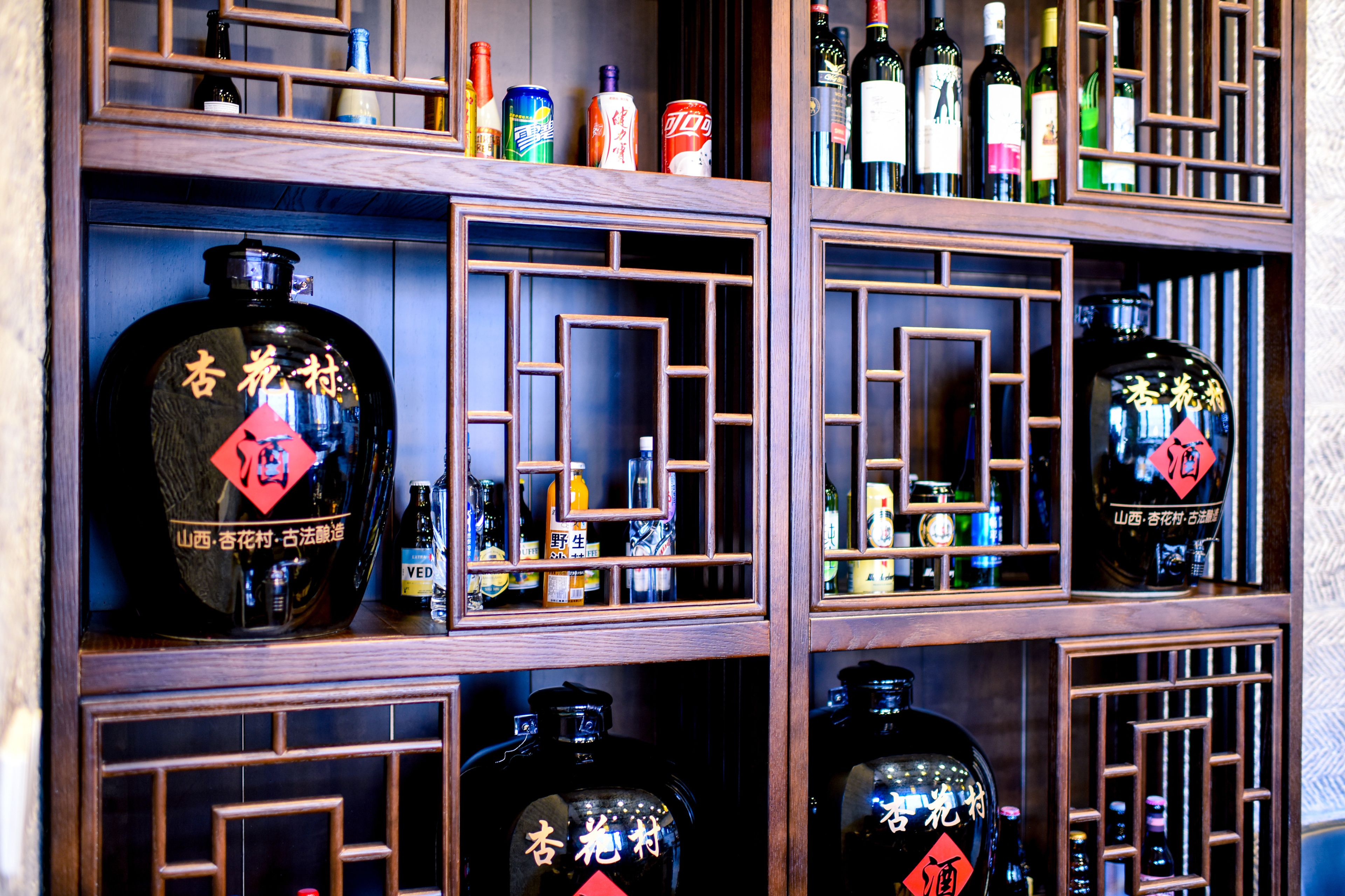A display of various liquor bottles in wooden shelves with geometric patterns.