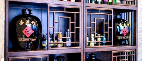 A display of various liquor bottles in wooden shelves with geometric patterns.