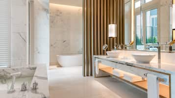 A modern bathroom with a large bathtub, a double sink vanity, and a large mirror.