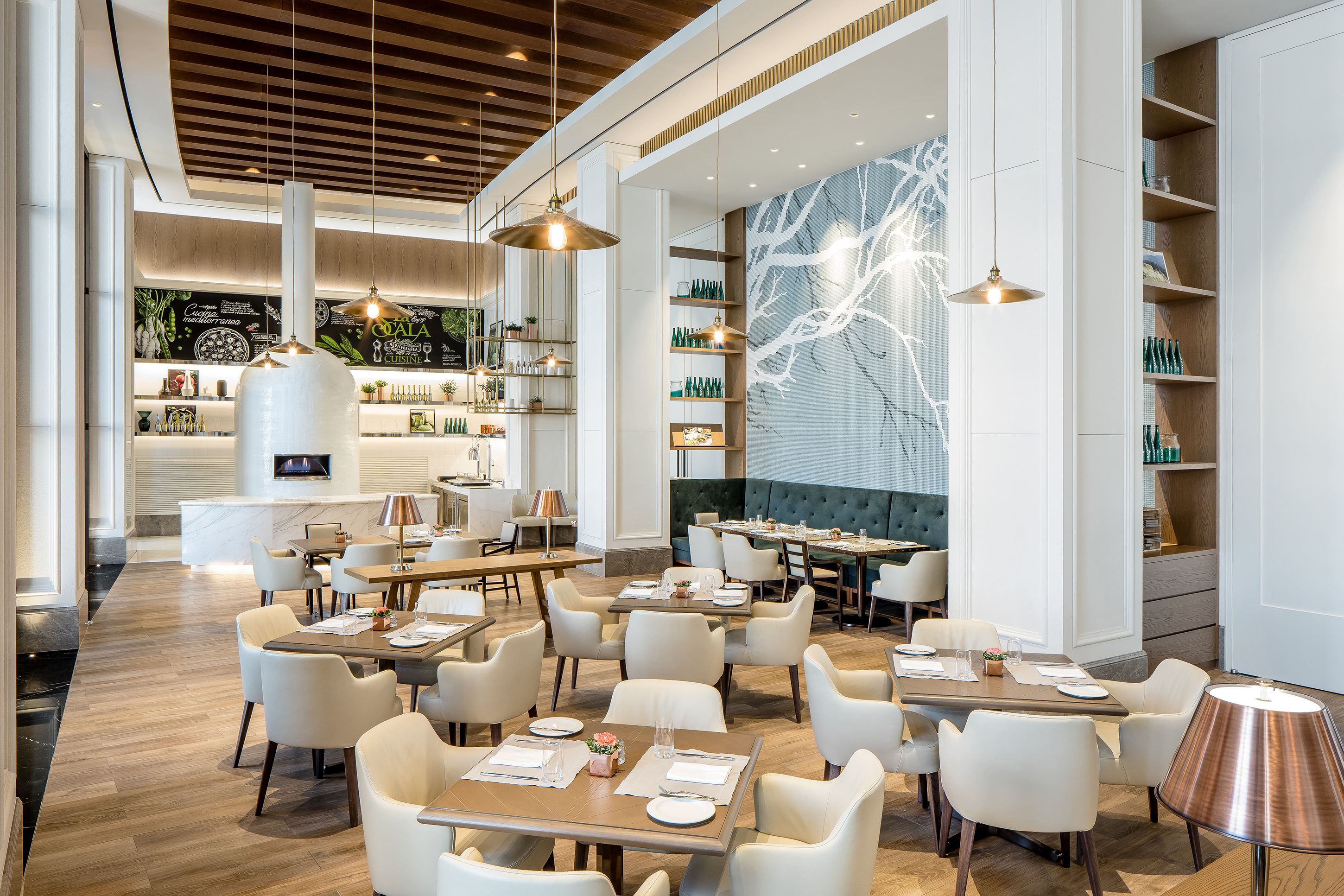 A modern restaurant with multiple dining tables and chairs, a bar area, and a large mural on the wall.