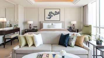 A hotel room with a large bed, a sofa, a coffee table, and a desk with a lamp.