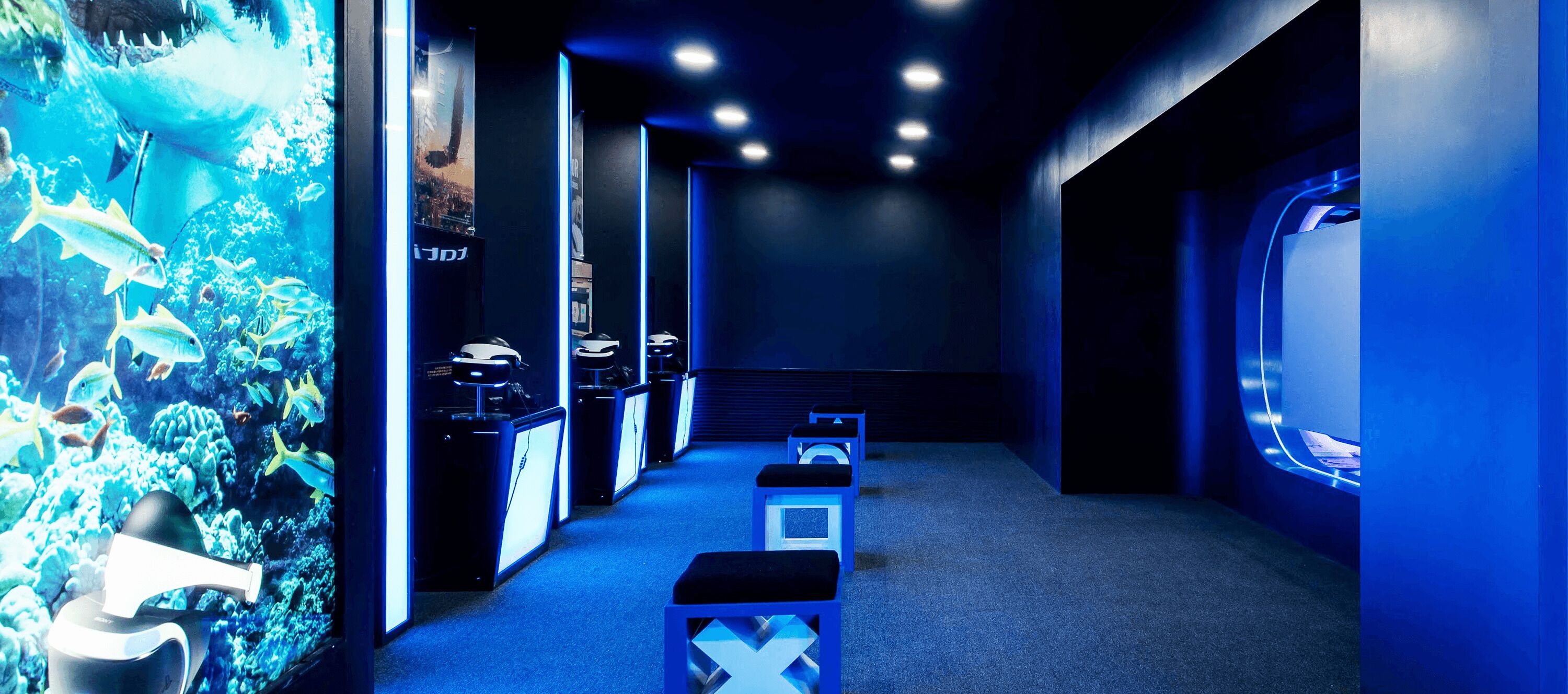 A hallway with aquarium walls, benches, and a large screen.