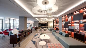 Een moderne lobby met een centraal zitgedeelte, een grote boekenkast en een uniek plafondontwerp.