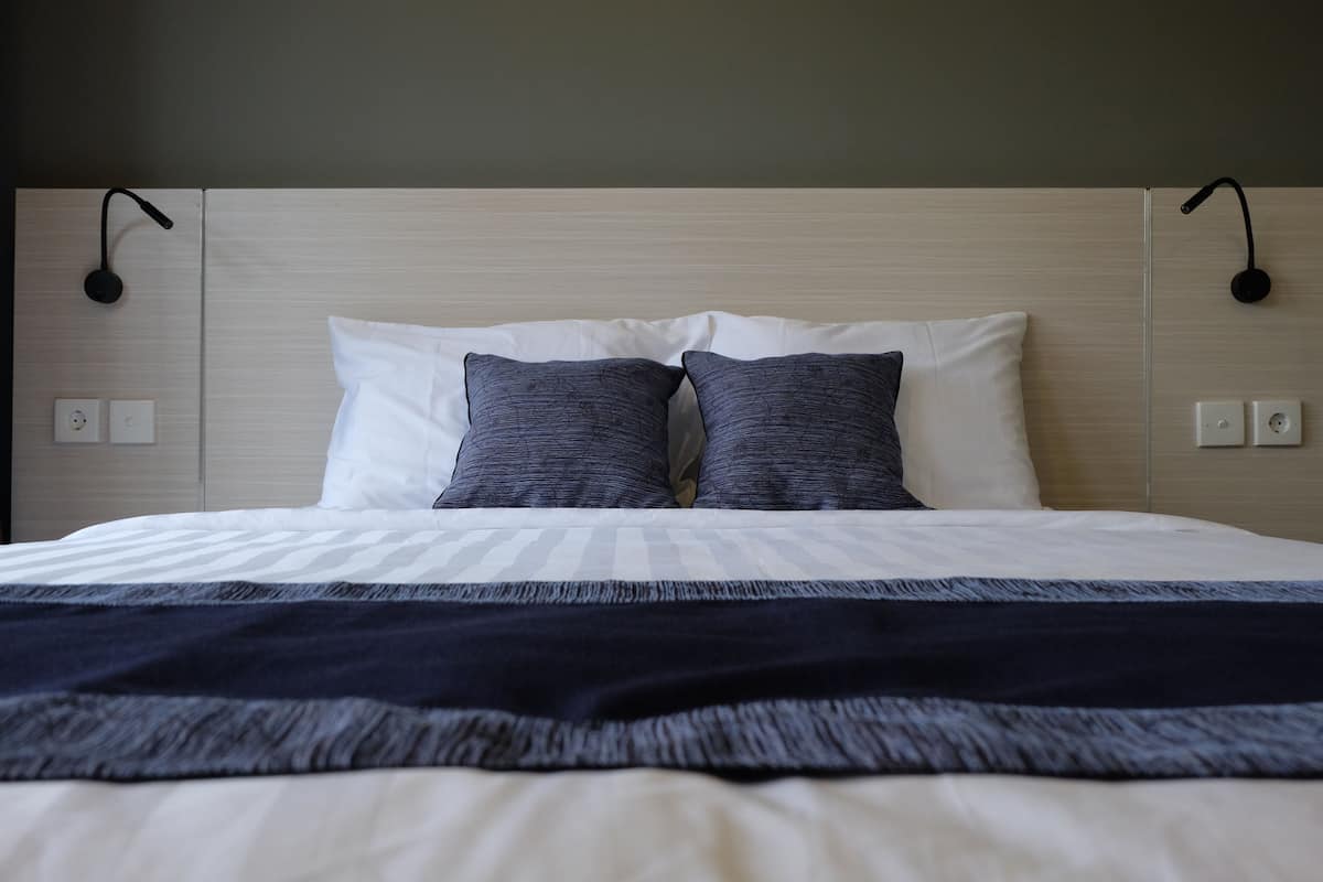 A neatly made bed with a striped bedspread, two pillows, and a dark throw blanket.