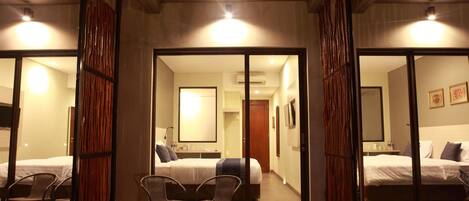 A hotel room with a large mirror, a bed, two chairs, and a small table.