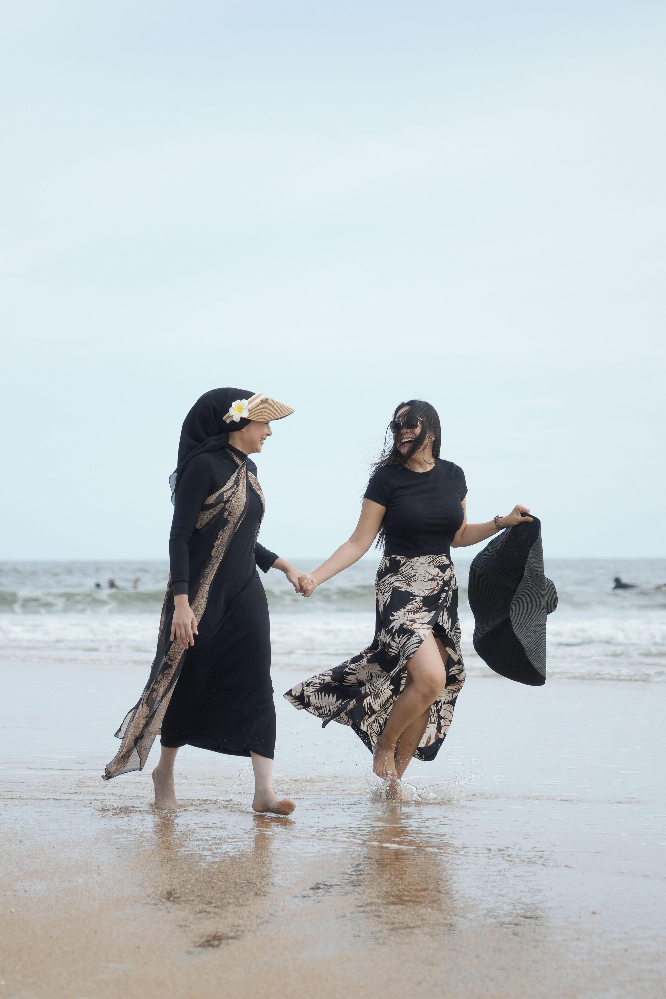 Two people holding hands on a beach.