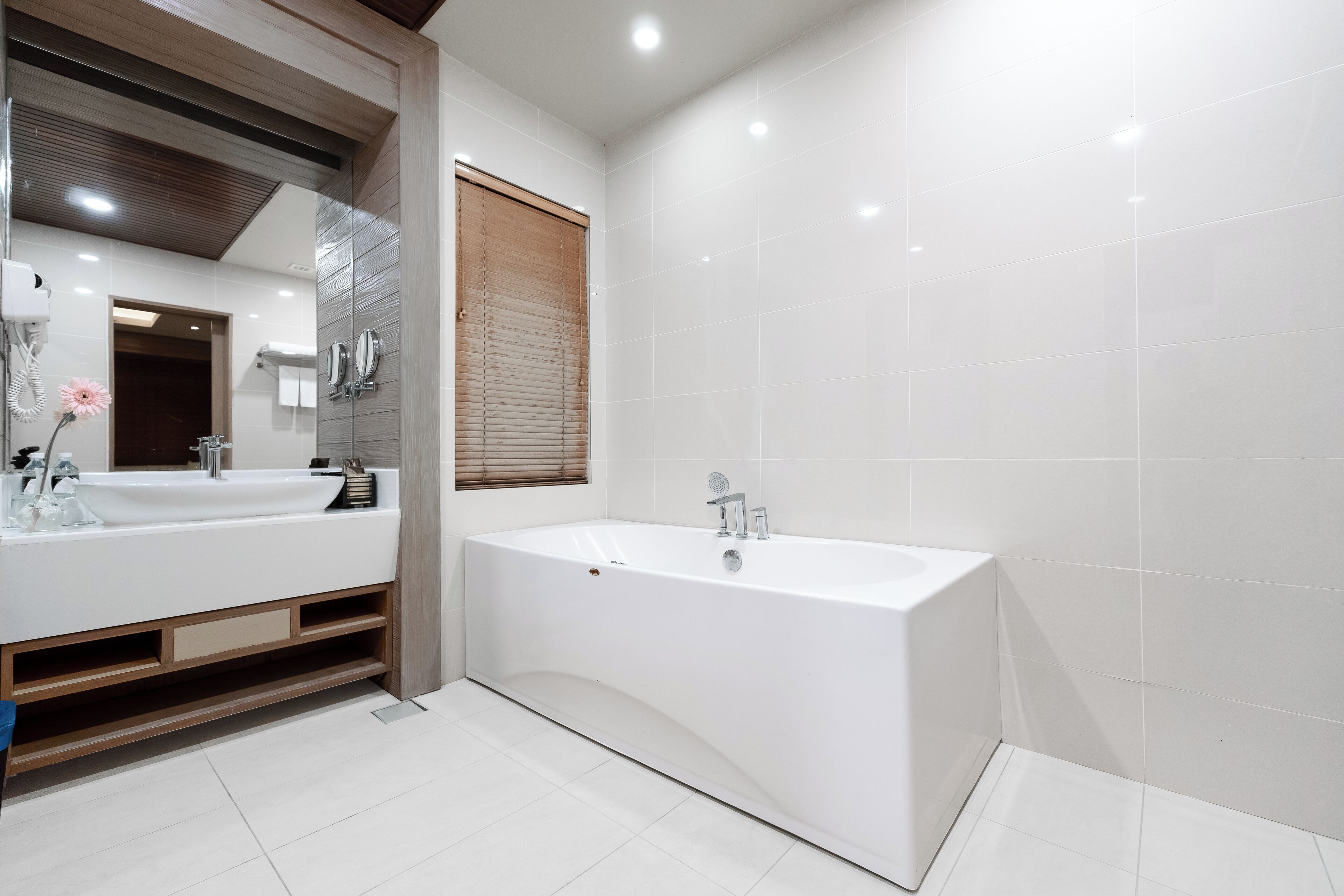 A modern bathroom with a large bathtub, two sinks, and a vanity with storage.