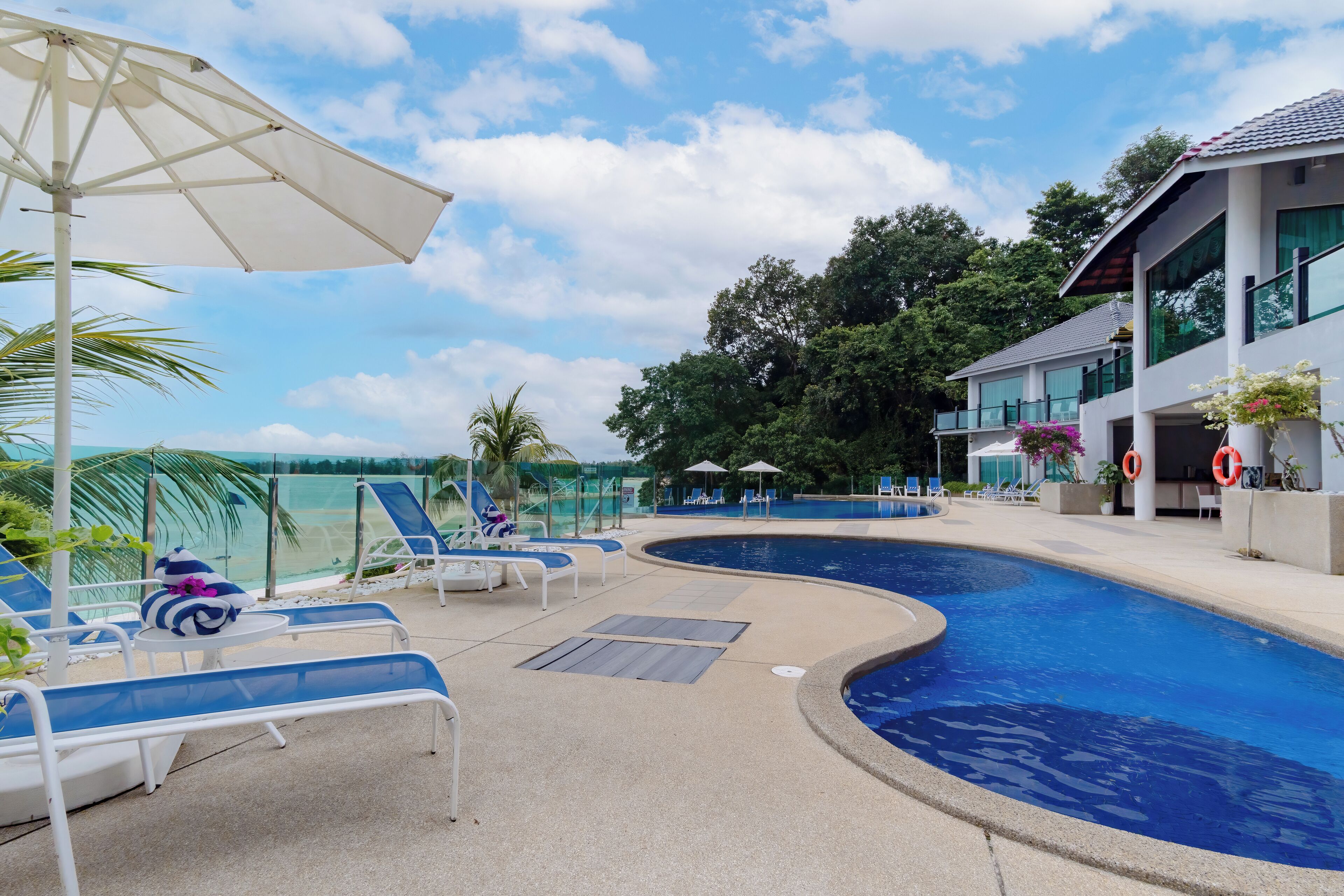 A swimming pool area with lounge chairs and umbrellas.