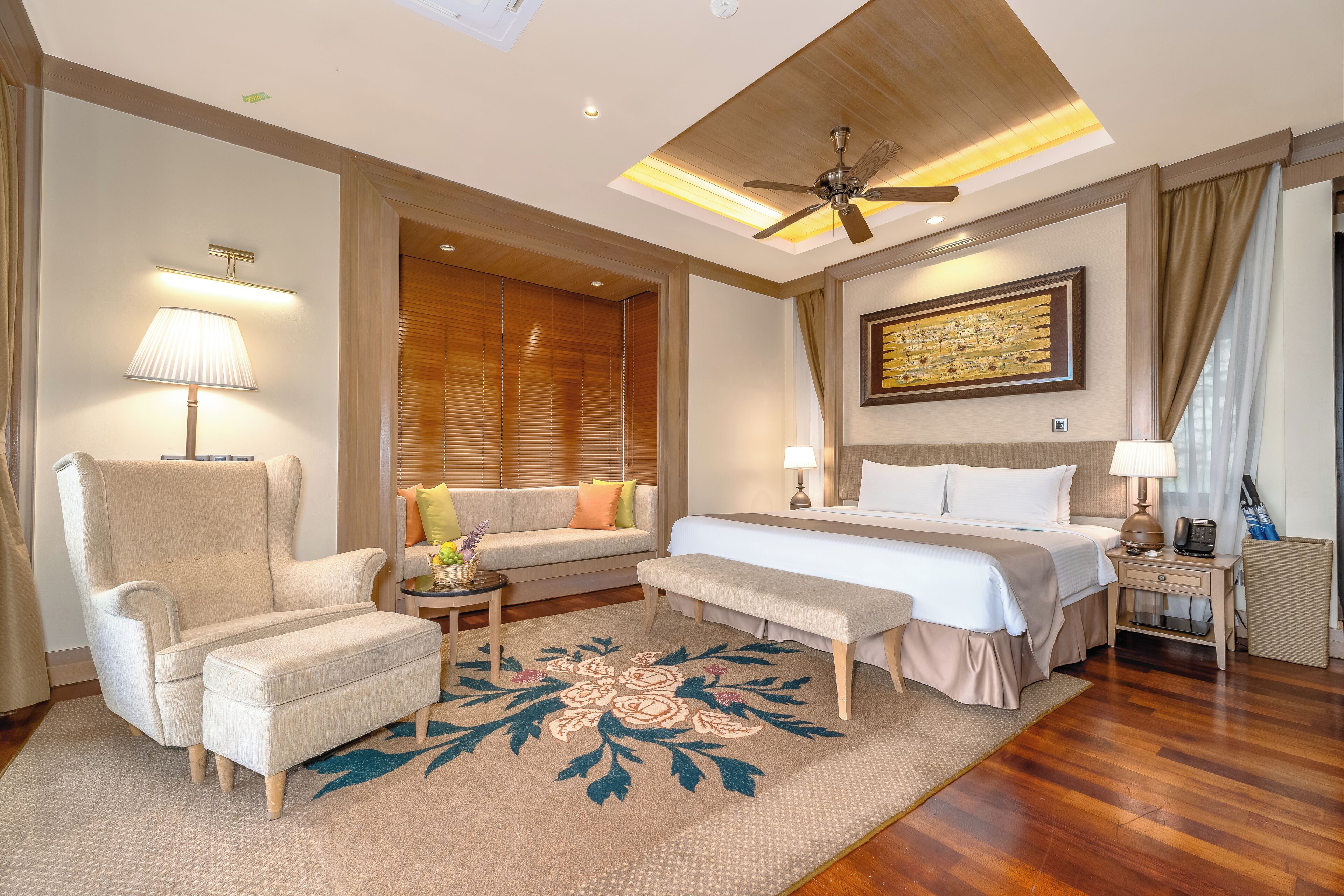 Une chambre d’hôtel comprenant un lit, un canapé, une chaise, un bureau et un ventilateur de plafond.