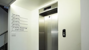 An elevator with a digital display and a wall-mounted emergency exit sign. - Hotel Park Hill Myeongdong (Seoul)