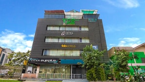 A multi-story hotel with signs for TBC, FABHOTELS, and ASTRA. - FabHotel VJR HSR (Bengaluru)