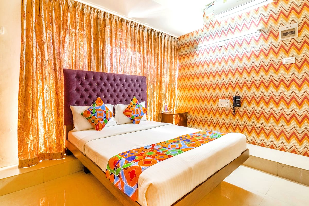 A hotel room with a large bed, a tufted headboard, and a colorful geometric-patterned bedspread.