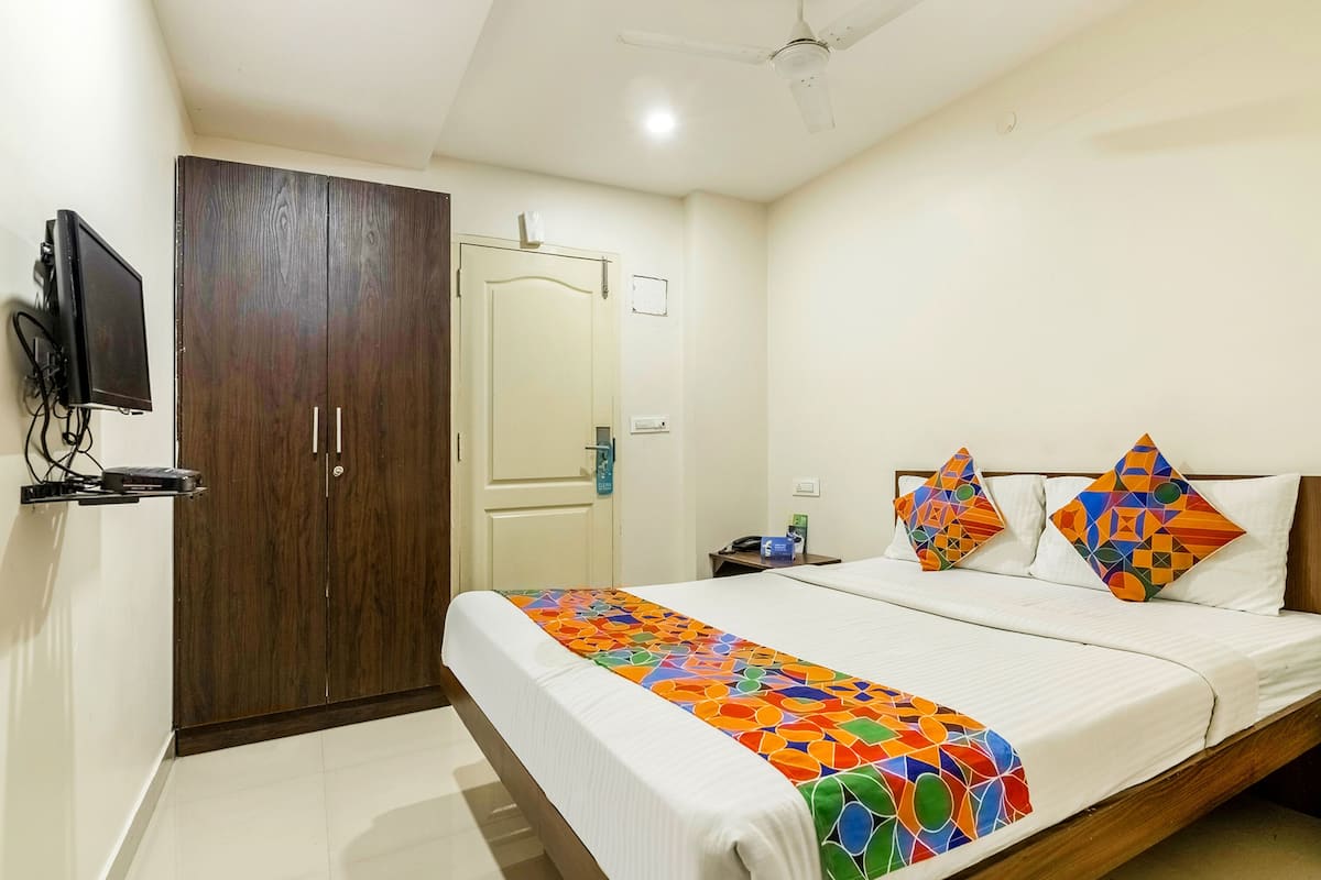 A hotel room with a bed, a wardrobe, a television, and a ceiling fan.