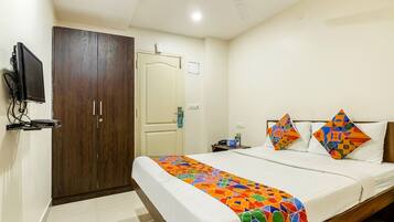 Una habitación de hotel con cama, armario, televisor y ventilador de techo.