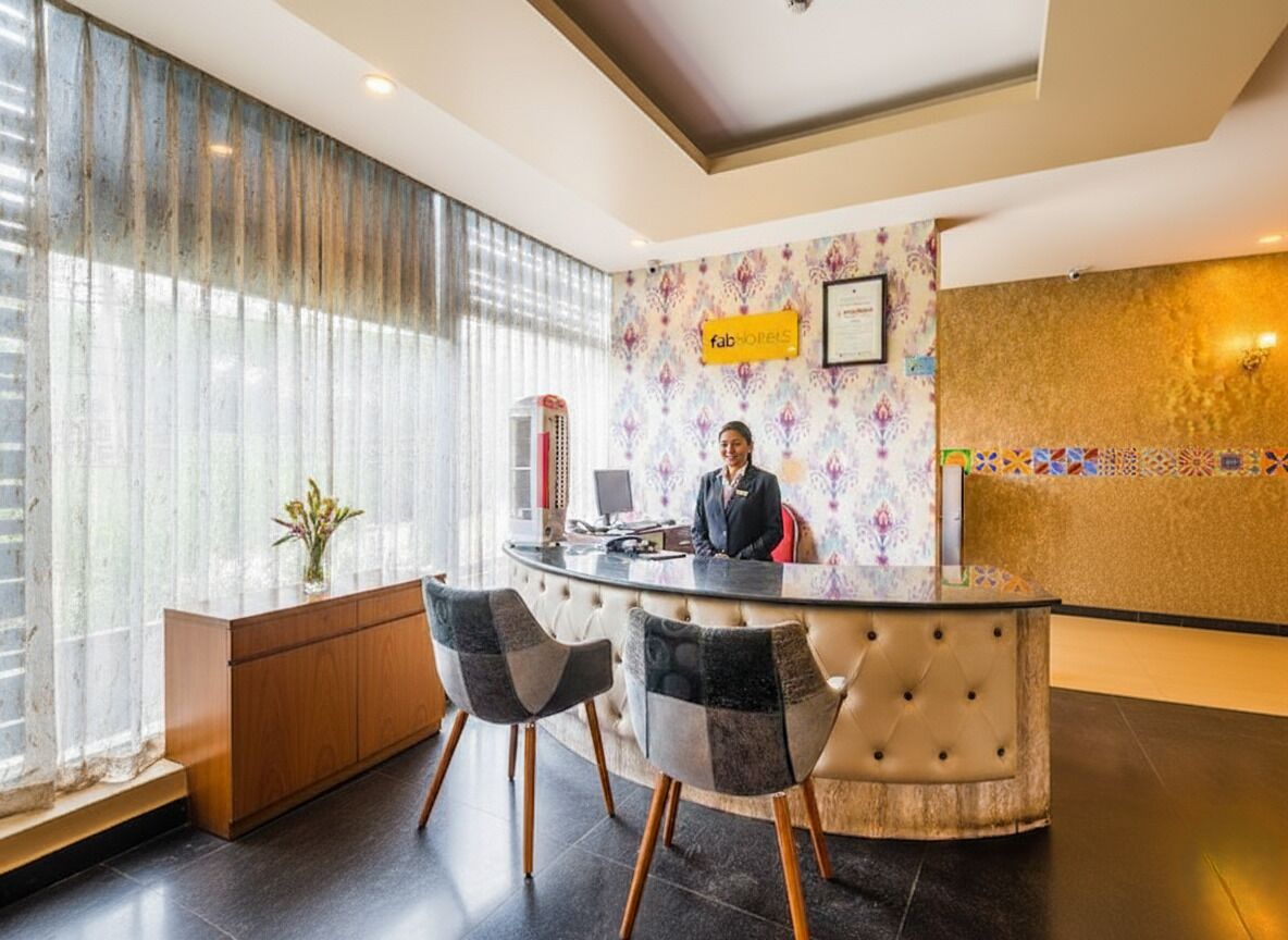 A hotel reception area with a receptionist, a counter, and two chairs.