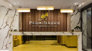 Bancada de recepção com tampo de mármore e painel de madeira ao fundo com o nome do hotel.