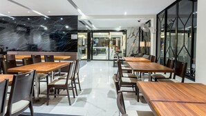 Um restaurante moderno com paredes de mármore, mesas e cadeiras de madeira.