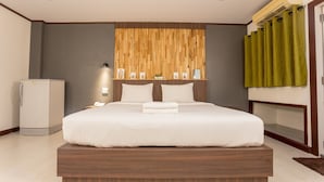 Quarto de hotel moderno com uma cama grande, armário embutido, minibar e ar condicionado fixado na parede.