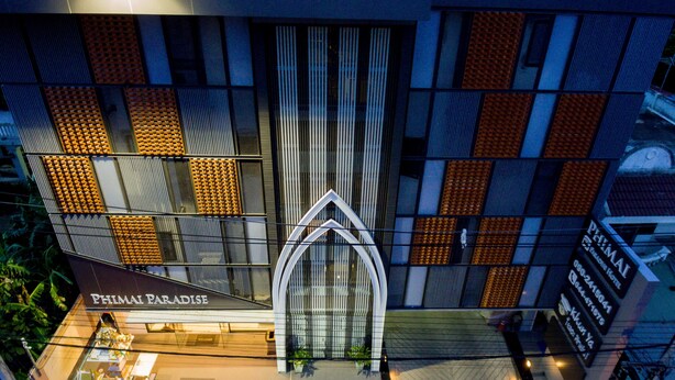 Um hotel moderno com entrada imponente, escadaria visível para o saguão e vista clara do entorno urbano.
