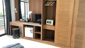 A modern room with a wooden desk, a television, a mini-fridge, a coffee maker, and a wardrobe. - Benjamin Resort (Kamala)