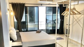 A modern hotel room with a large bed, a walk-in closet, a potted plant, and a view of the outdoors. - Benjamin Resort (Kamala)