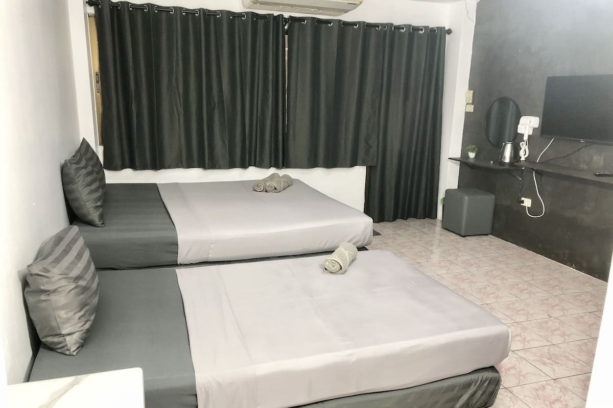 A room with two beds, a TV, and a small table with a kettle.