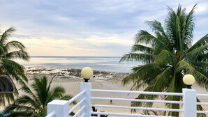 A balcony with a view of a beach, palm trees, and a railing with spherical finials. - Benjamin Resort (Kamala)