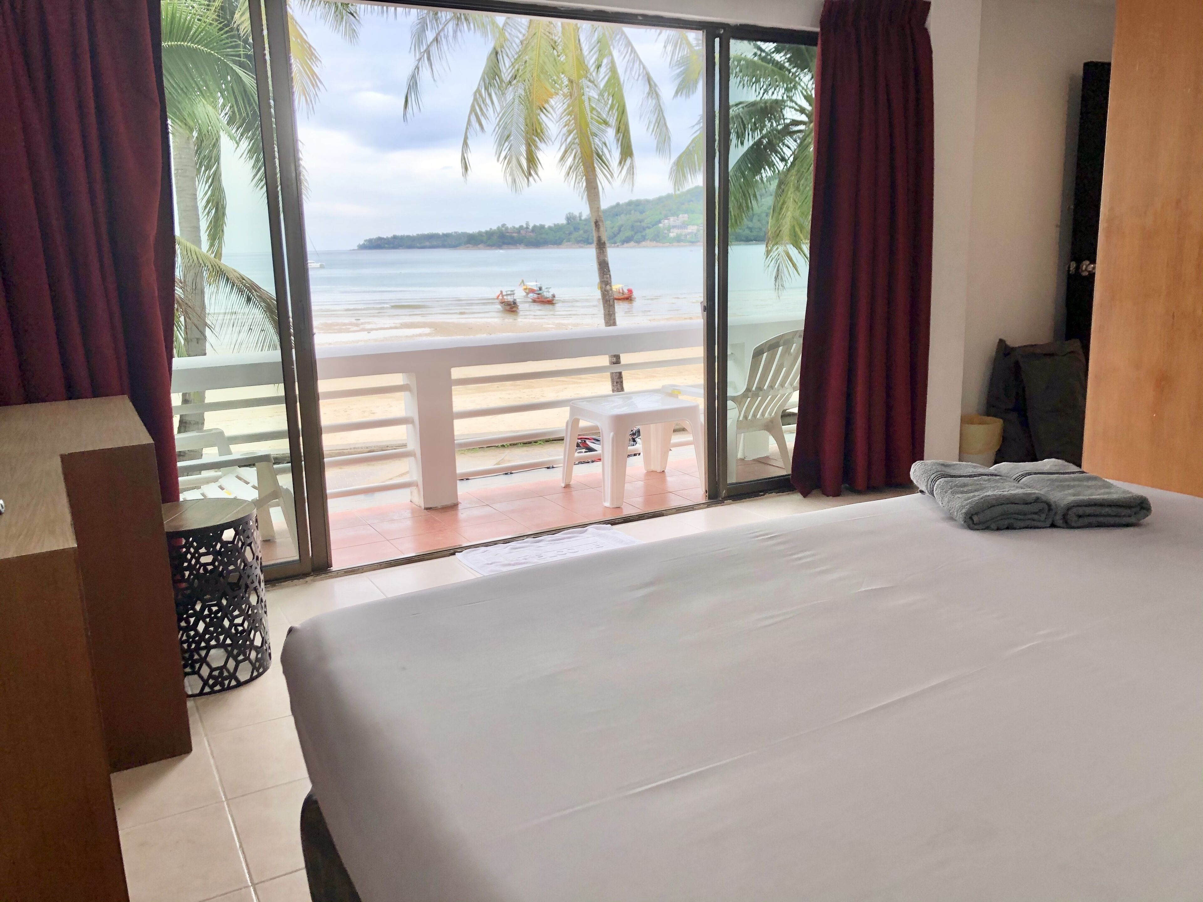 Une chambre d’hôtel avec un grand lit, une vue sur la plage et un balcon équipé d’une table et de chaises.