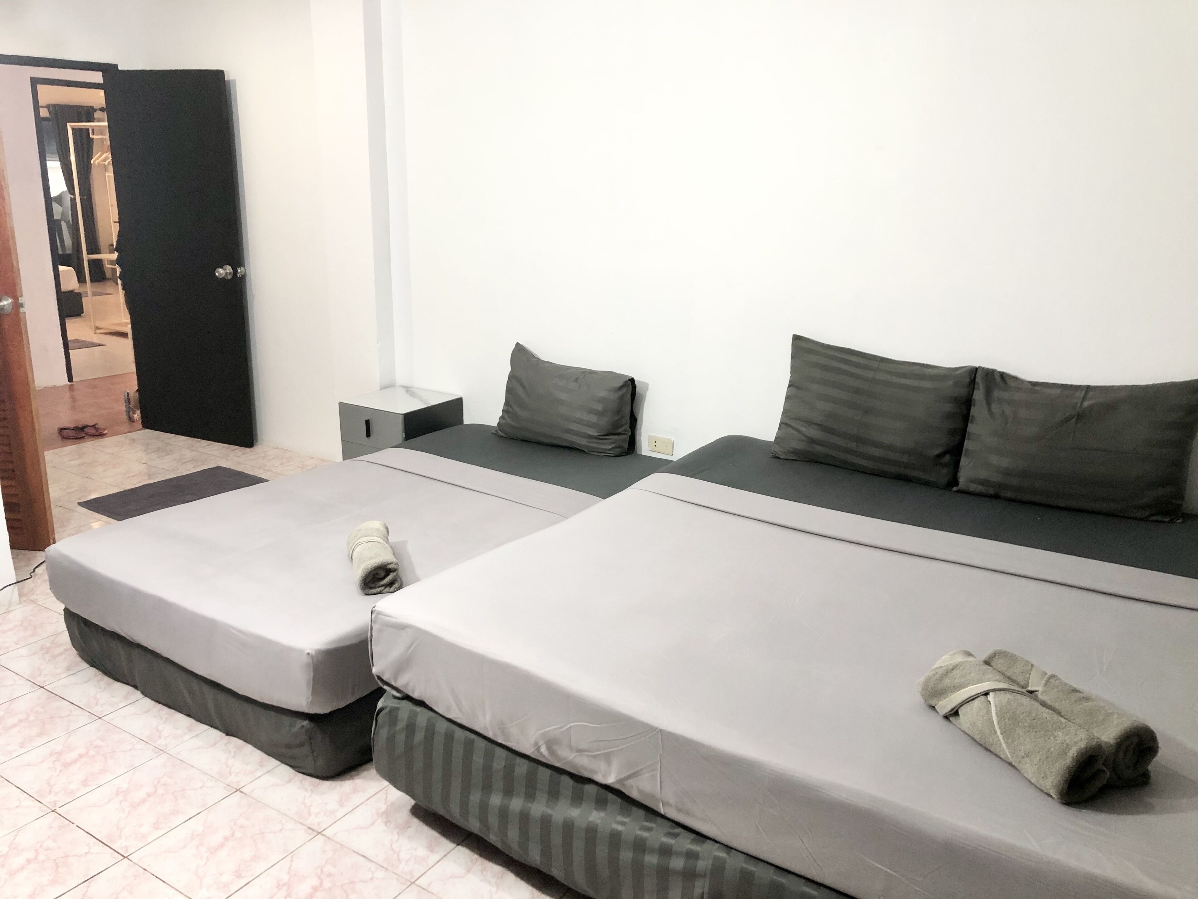 A room with two beds, a wardrobe, and a door leading to another room.