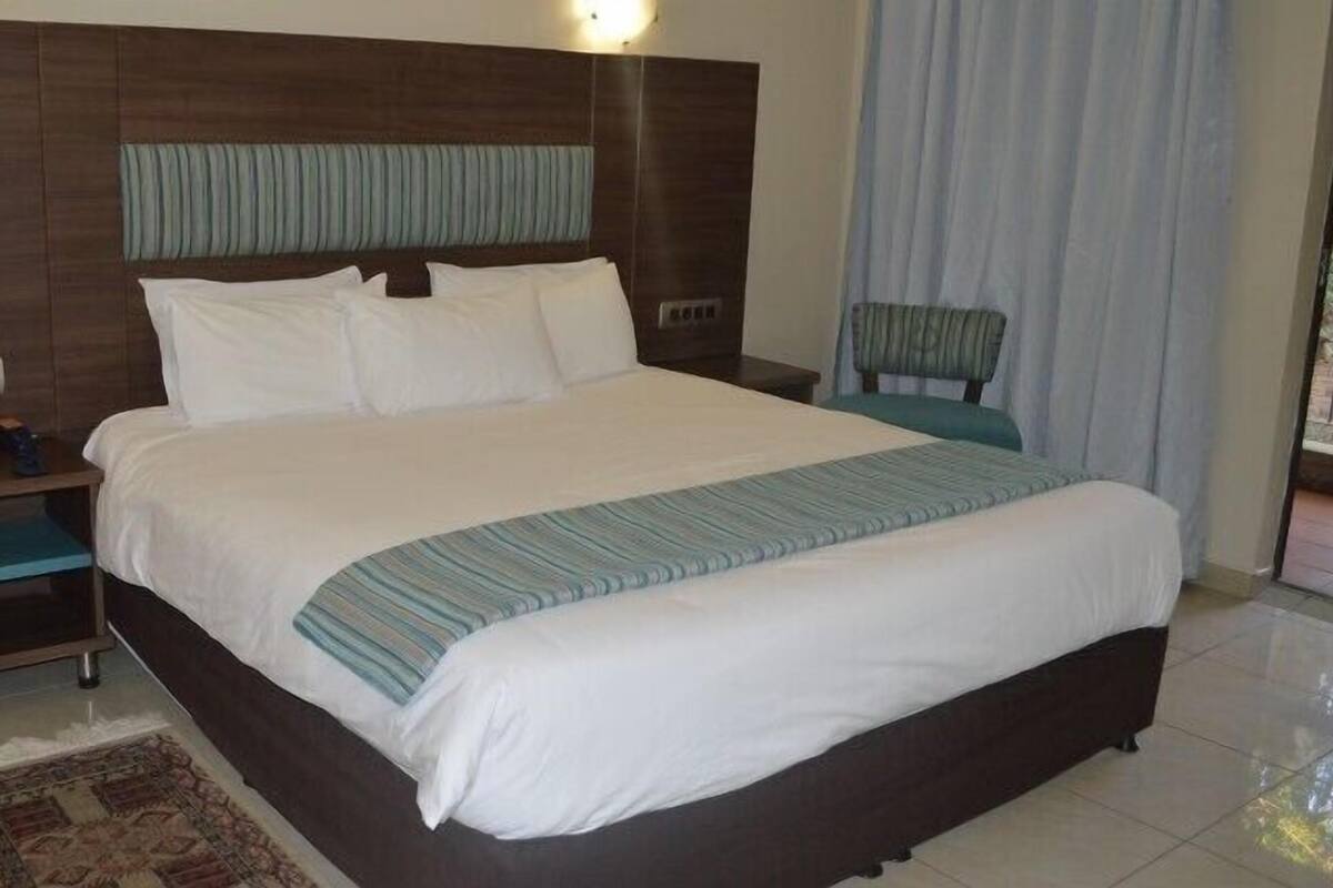 A large bed with a wooden headboard, a bedside table, and a chair.
