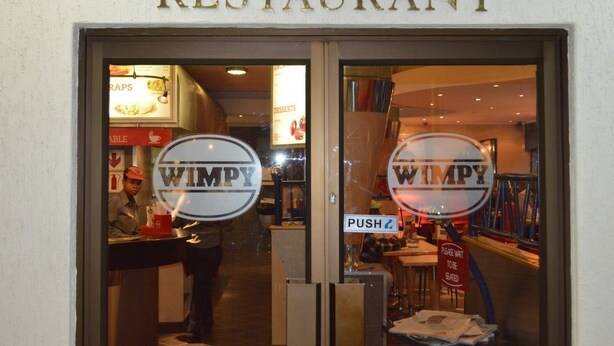 A restaurant entrance with a sign reading "RESTAURANT" and a logo "WIMPY" on the glass doors. - Desert Sands Motel (Palapye)