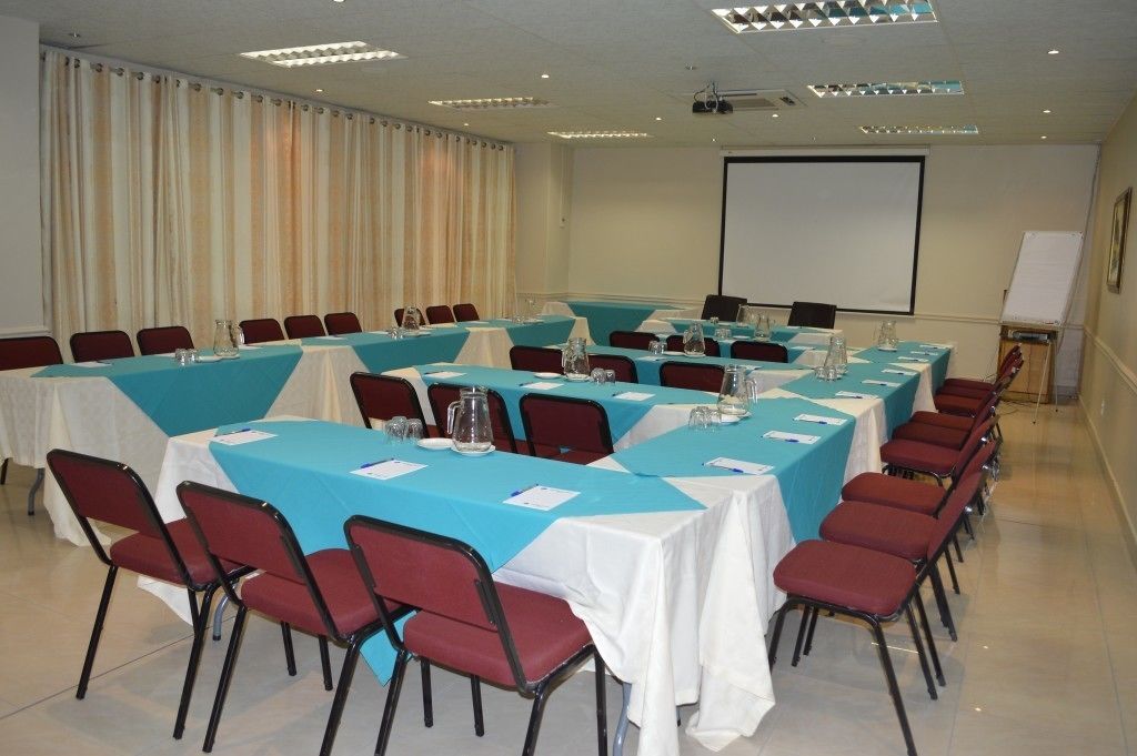 Una sala conferenze con diverse tavole, sedie e uno schermo per proiezioni.