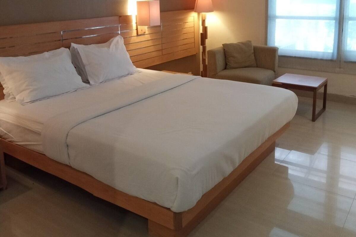 A neatly made bed with white linens, a wooden headboard, and bedside lamps.