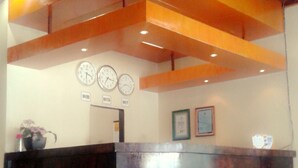 A reception desk with a wooden counter and a clock above it. - Serayu Hotel Timika (Timika)