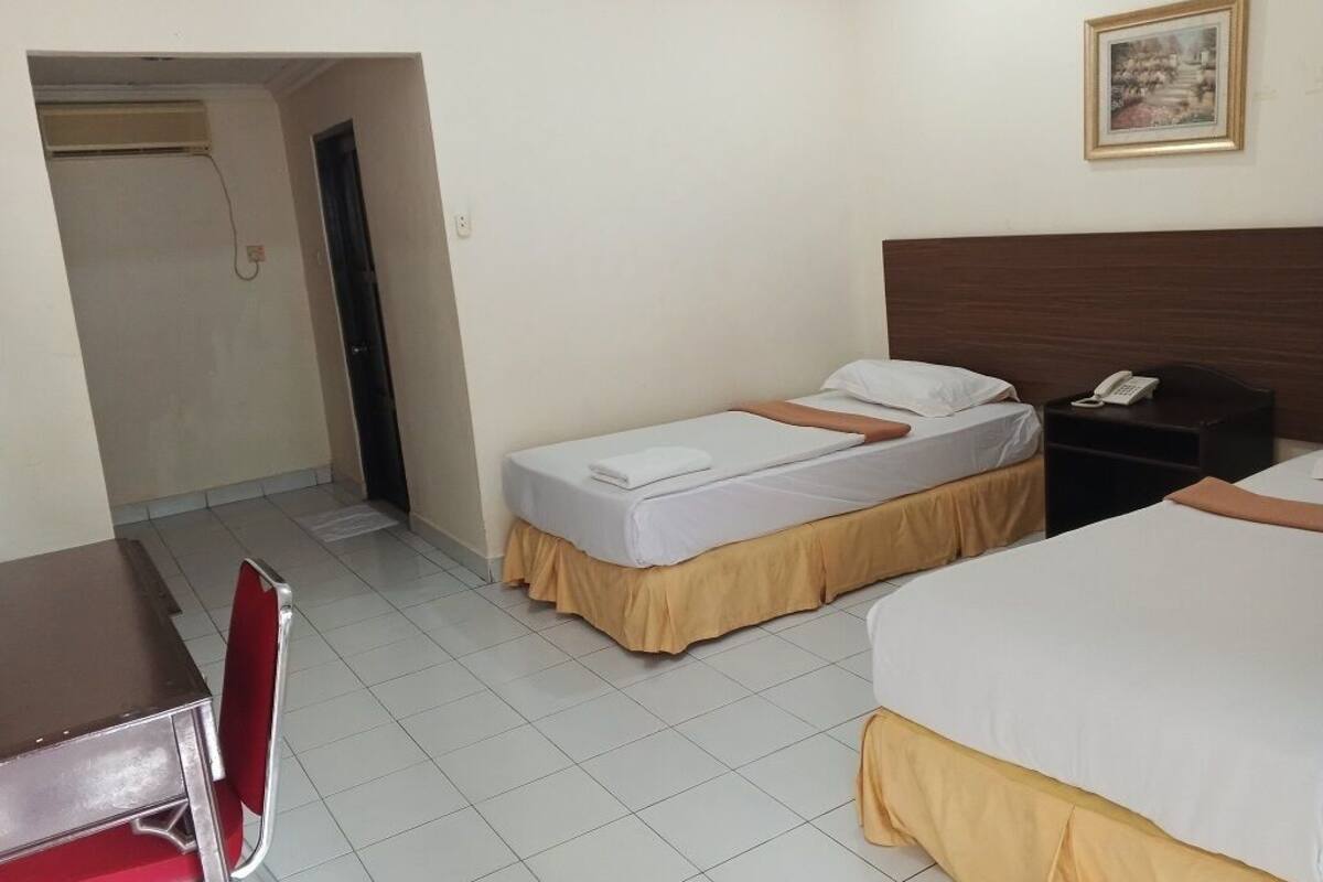 A hotel room with two beds, a desk, a chair, a bedside table with a phone, and a painting on the wall.