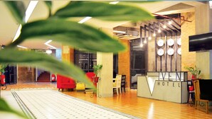 A hotel lobby with a reception desk, wooden flooring, and a large clock on the wall. - Viven Hotel (San Nicolas)