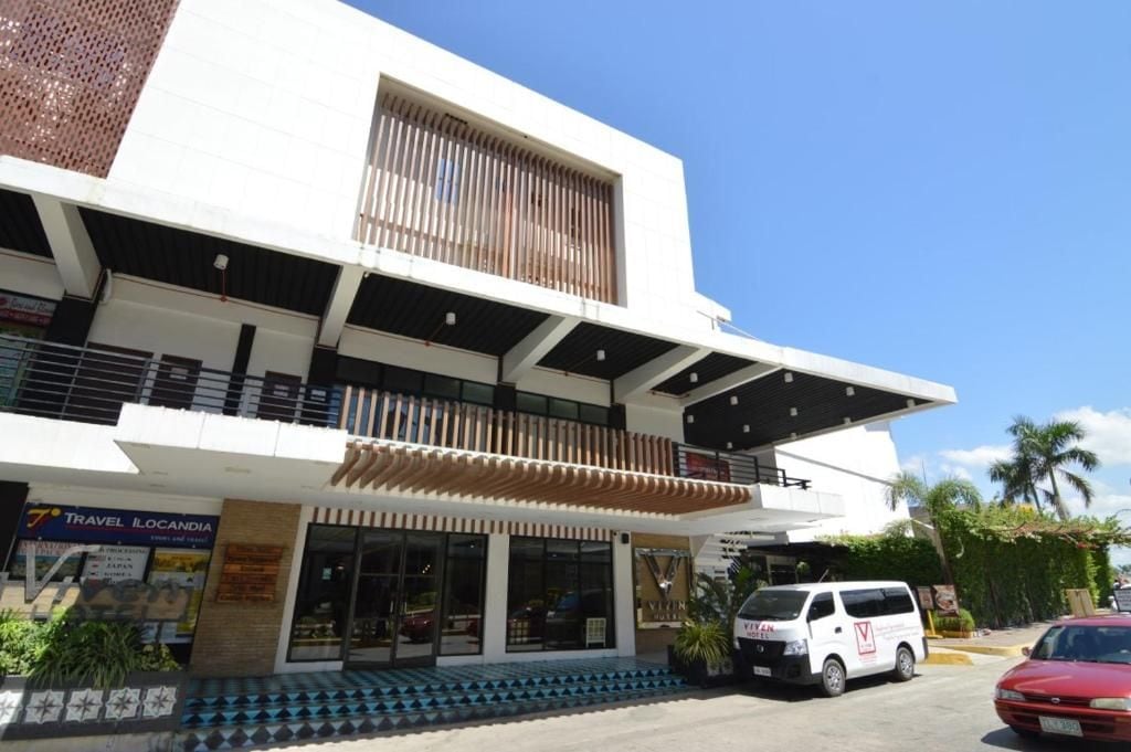 A modern building with a travel agency on the ground floor, a covered entrance, and a white van parked in front.