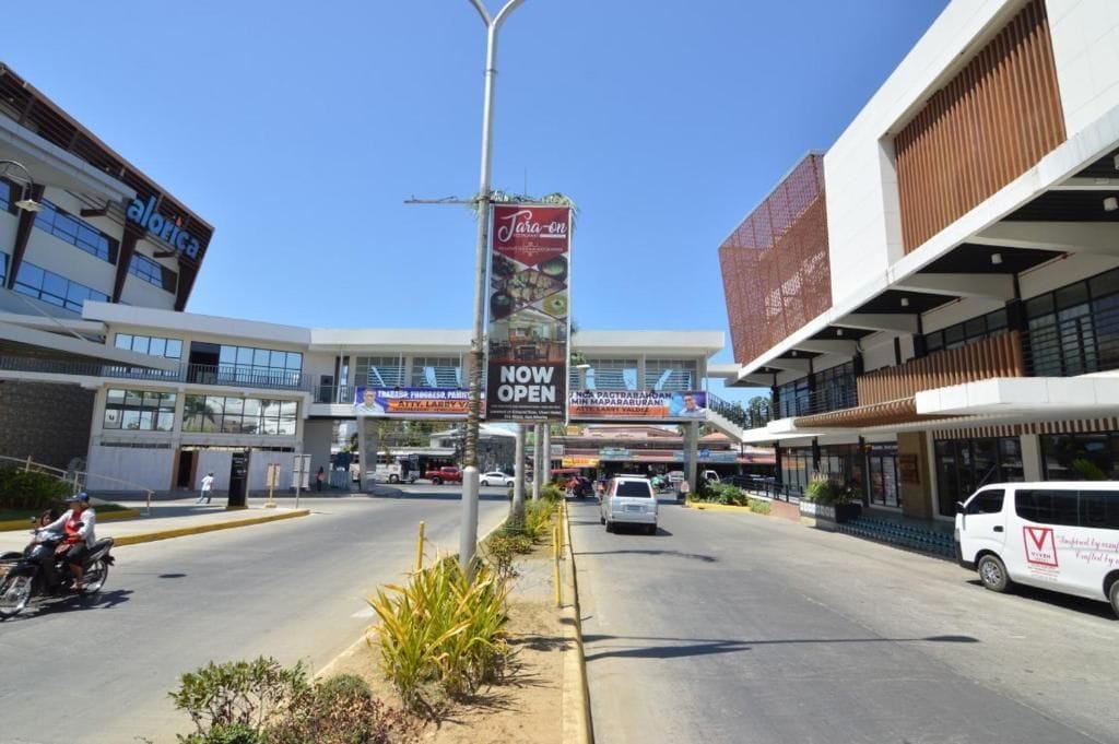 A street with a banner advertising a new business opening.