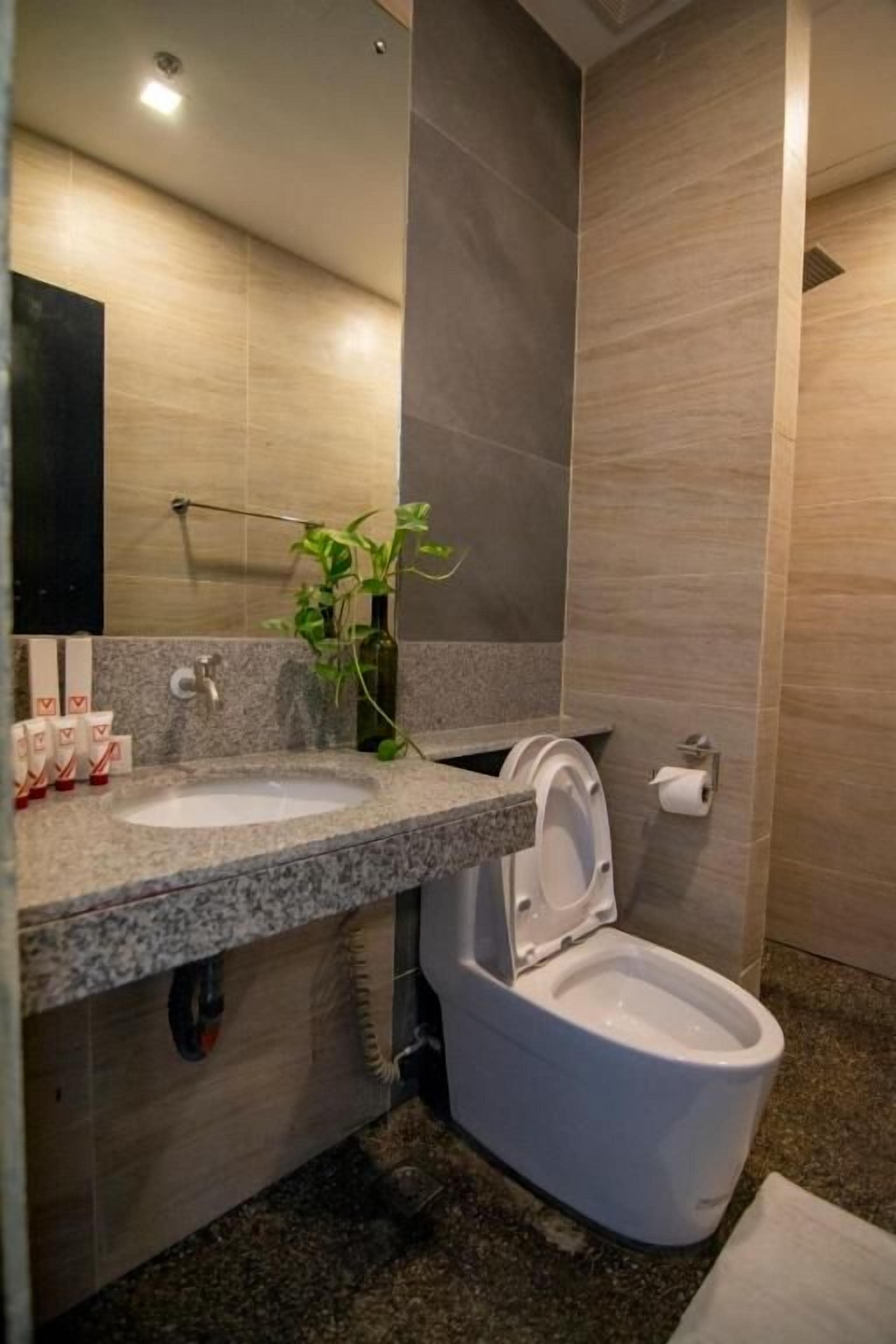 A bathroom with a granite countertop sink, a white toilet, and a mirror above the sink.
