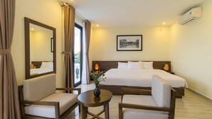 A hotel room with a large bed, two armchairs, a small table, a mirror, and a picture on the wall. - Terrace Villa Hoi An (Da Nang)