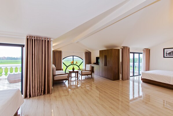 A spacious room with a large window, a bed, a desk, and a view of a green landscape. - Terrace Villa Hoi An (Da Nang)