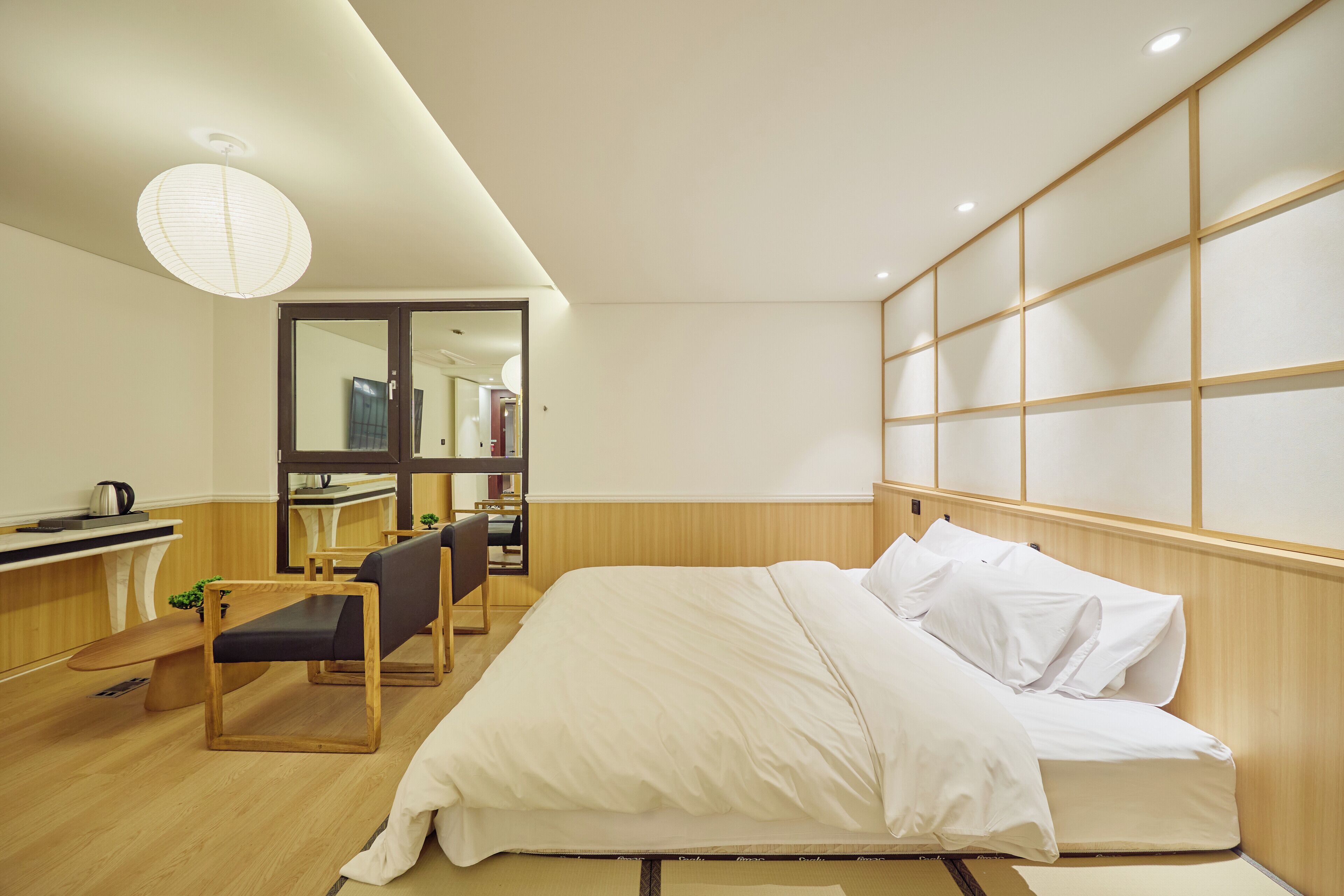 A hotel room with a bed, a desk, a chair, and a large mirror.