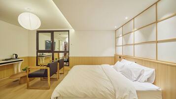 A hotel room with a bed, a desk, a chair, and a large mirror.
