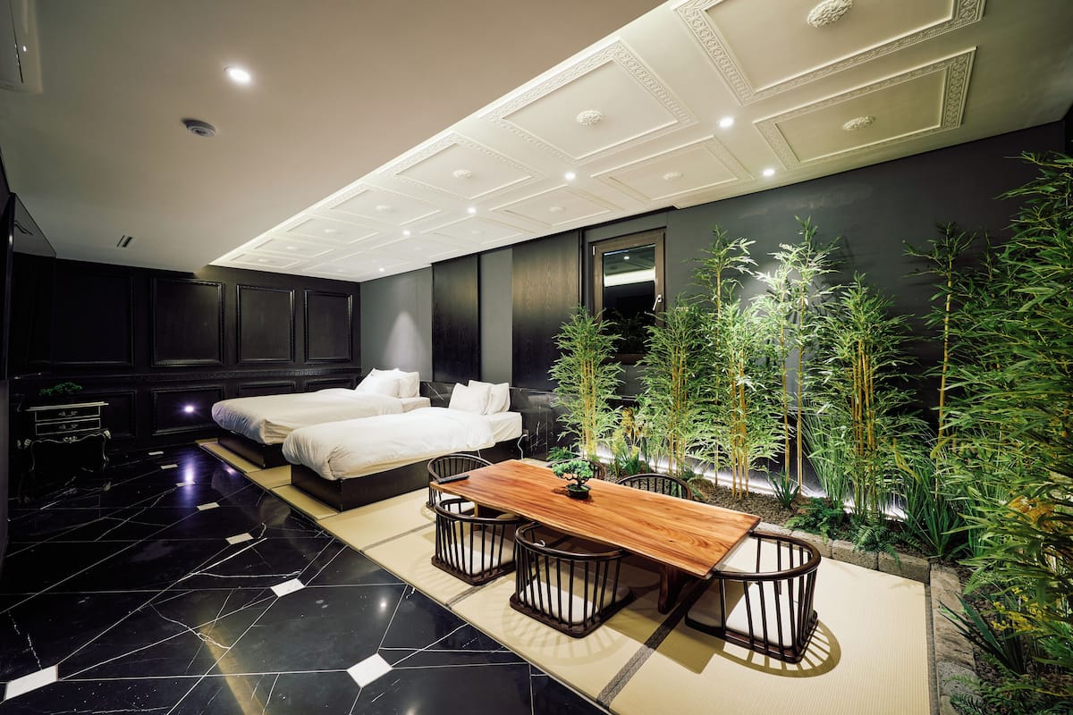 A modern hotel room with a large bed, a wooden dining table, and a small indoor garden.