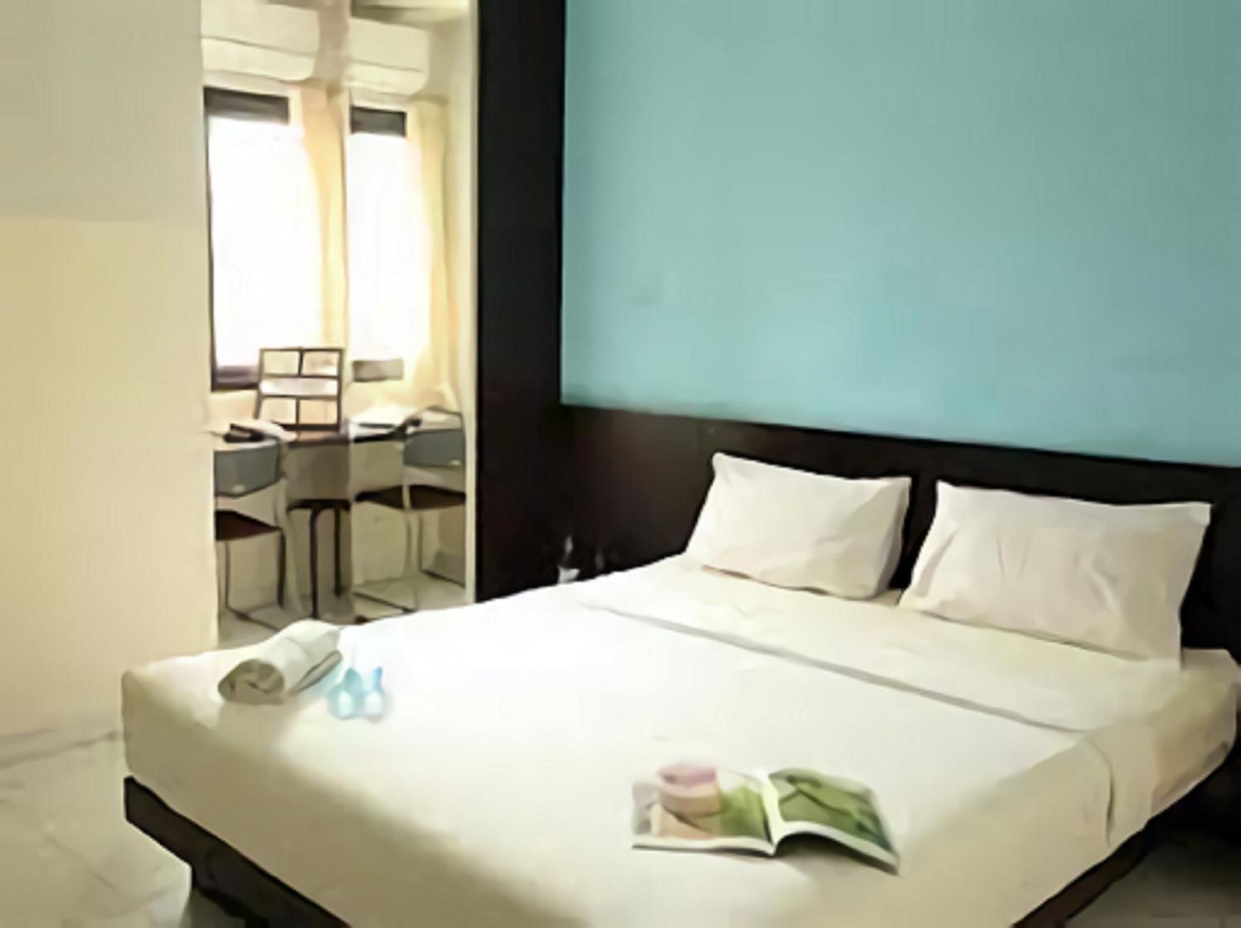 A hotel room with a bed, a desk, and a chair.