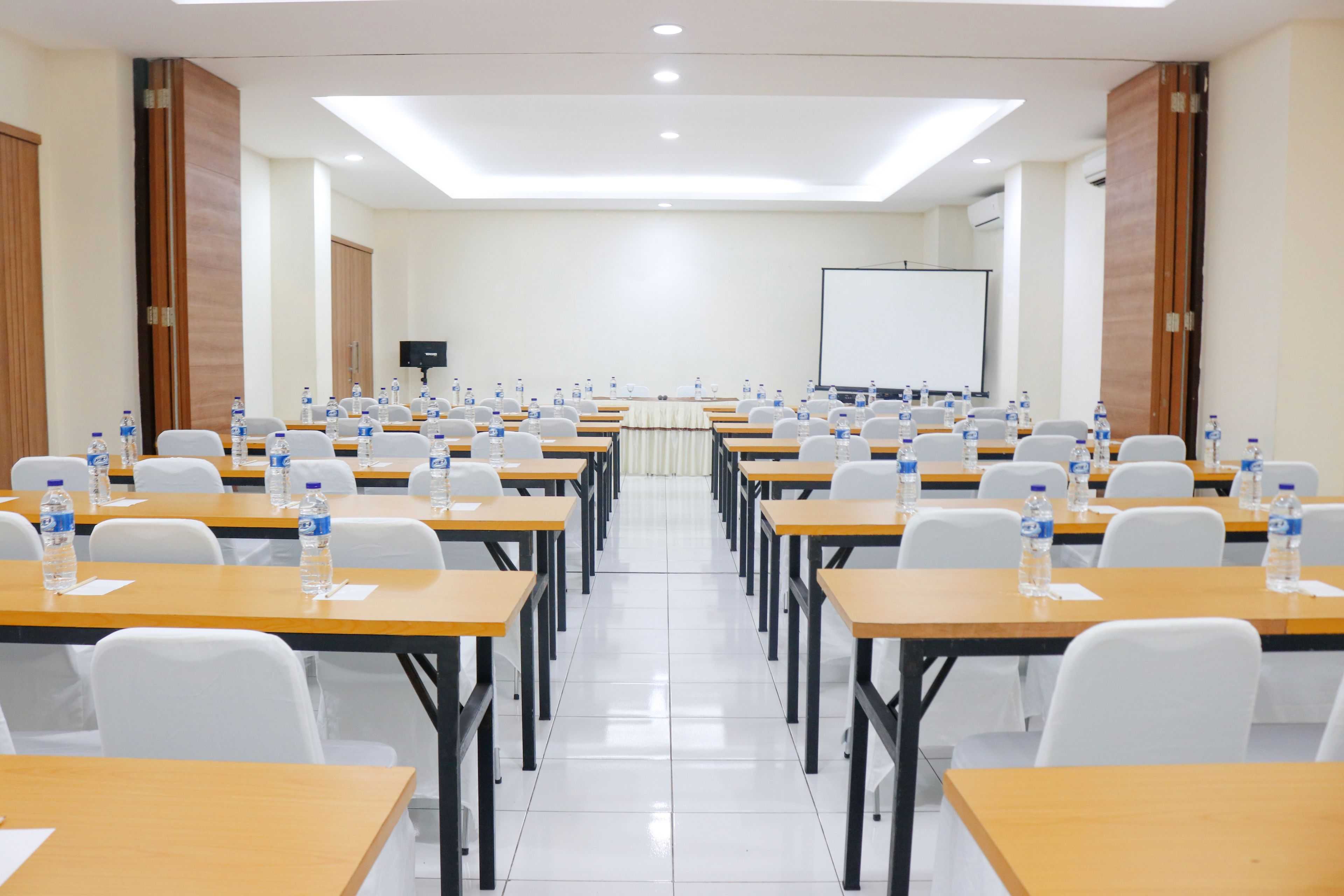 Un salón de conferencias con mesas, sillas y botellas de agua.