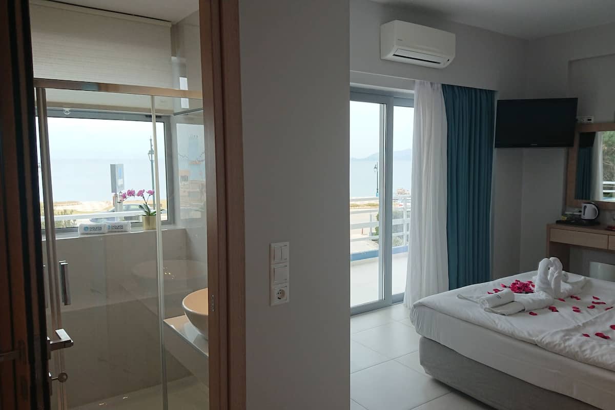 Une chambre d’hôtel avec un lit, une télévision, une salle de bain et un balcon offrant une vue.