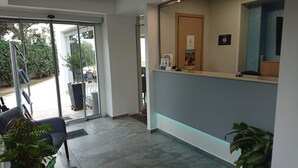 A reception area with a glass door leading outside, a reception desk, and a chair.